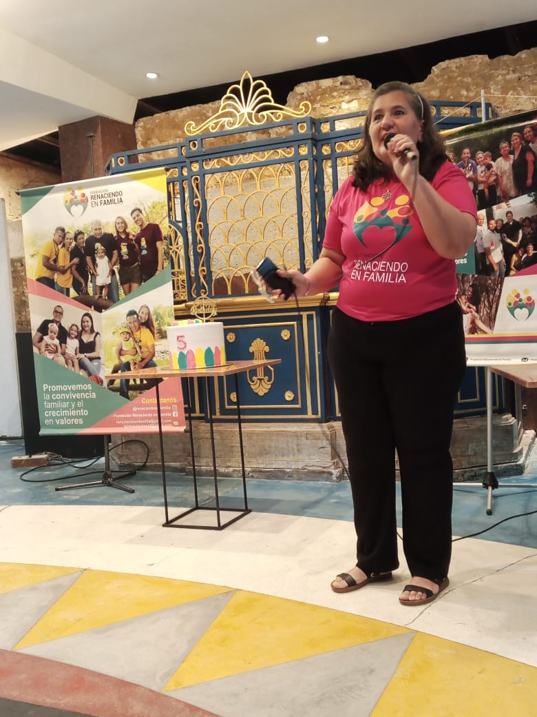 man wearing a black jacket, white shirt, blue jeans, and brown boots, playing a white electric guitar while sitting on an amp